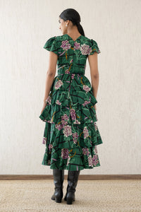 Back view of a woman wearing the Brigit dress in Tartan Rose Pine print. It features a cascading skirt of tiered ruffles, pin tucks under bust and waist, a V-neck, and cap sleeves.