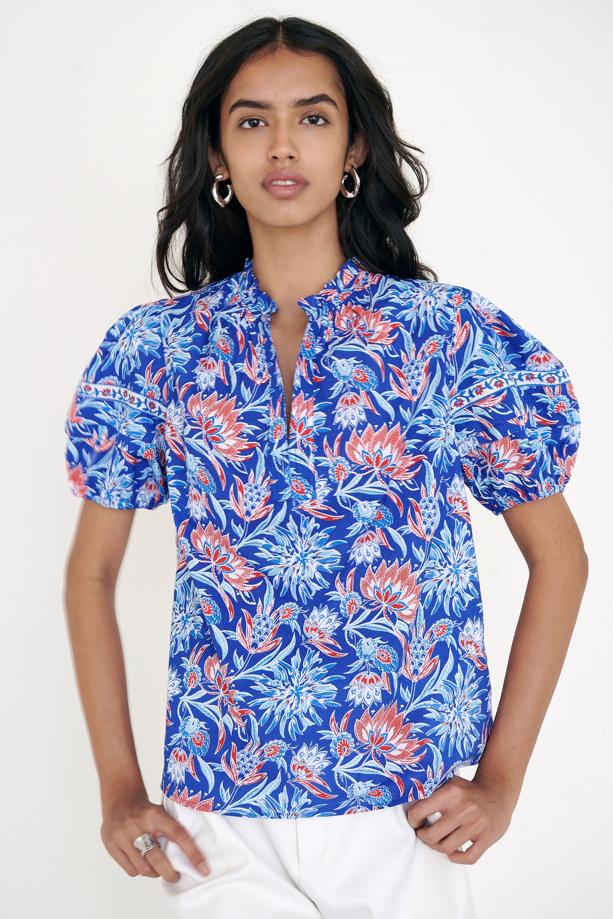 Front view of woman standing wearing the Bronte top in the Philippa print, featuring a front opening, delicate contrast trim, pleated sleeves, and a hand-screen-printed wildflower pattern.