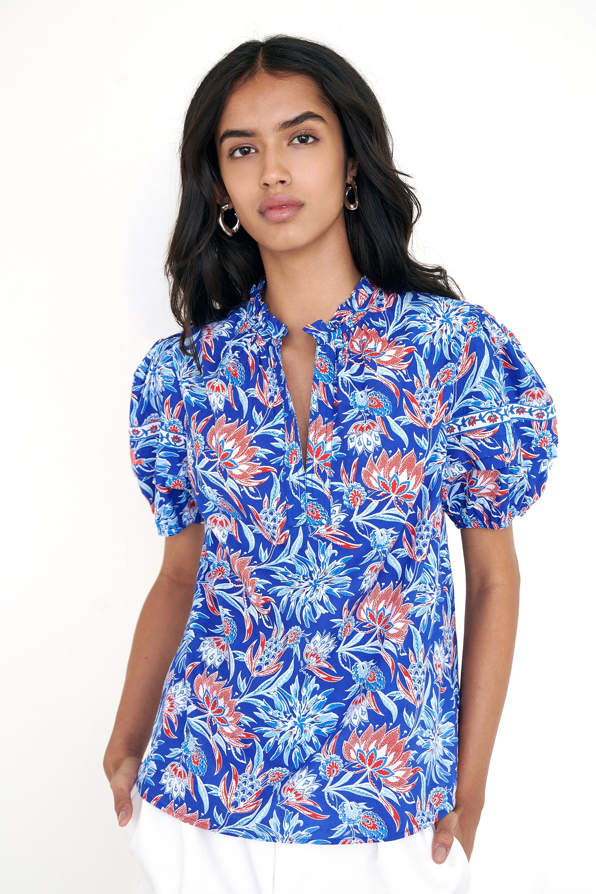 Front view of woman standing wearing the Bronte top in the Philippa print, featuring a front opening, delicate contrast trim, pleated sleeves, and a hand-screen-printed wildflower pattern.