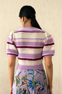 Back view of a woman wearing the Brushed Stripe Cardigan in Lilac, which hits at the waist, featuring a button placket, ribbed trim, and soft brushed yarn finish.