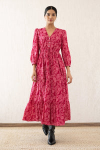 Front view of a woman wearing the Castor dress with soft puff sleeves and a gathered drawstring skirt in Tresse Winterberry print, a floral design. The dress is fully lined finished with side seam pockets.