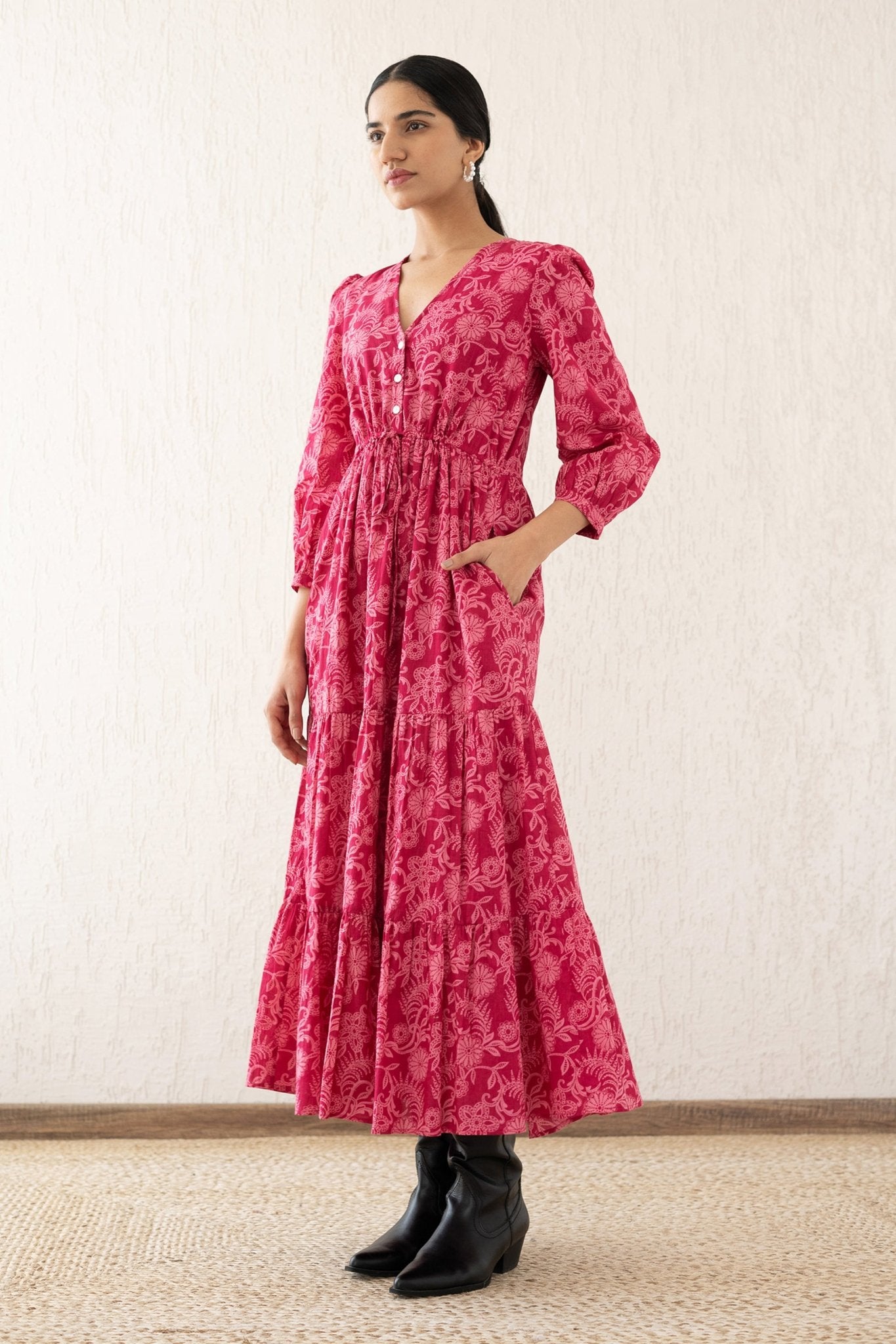 Side view of a woman wearing the Castor dress with soft puff sleeves and a gathered drawstring skirt in Tresse Winterberry print, a floral design. The dress is fully lined finished with side seam pockets.