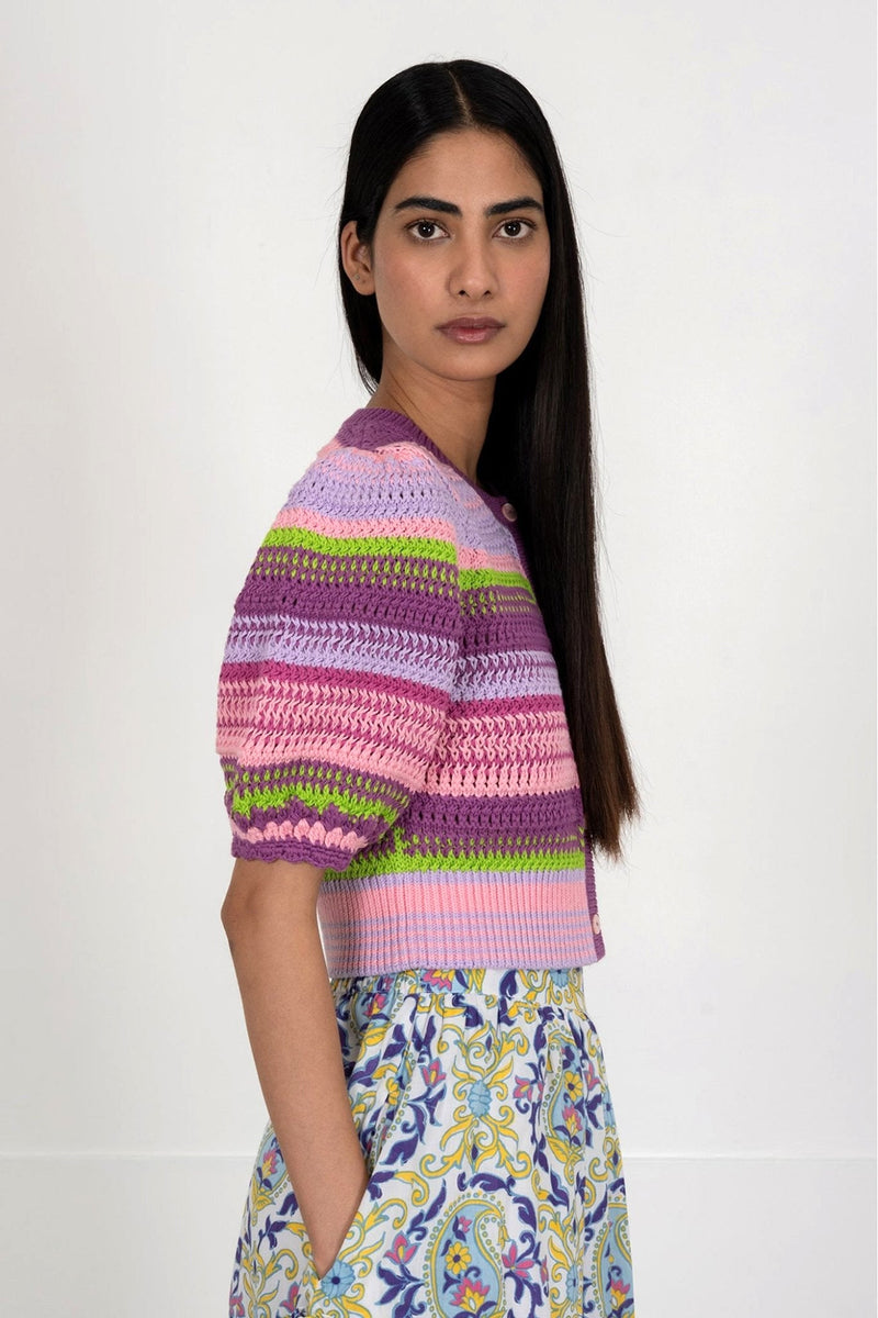 Side view of woman wearing the Celeste cardigan, a hand-crocheted piece in vibrant colors inspired by minerals. Perfect for layering over dresses or pairing with pants.