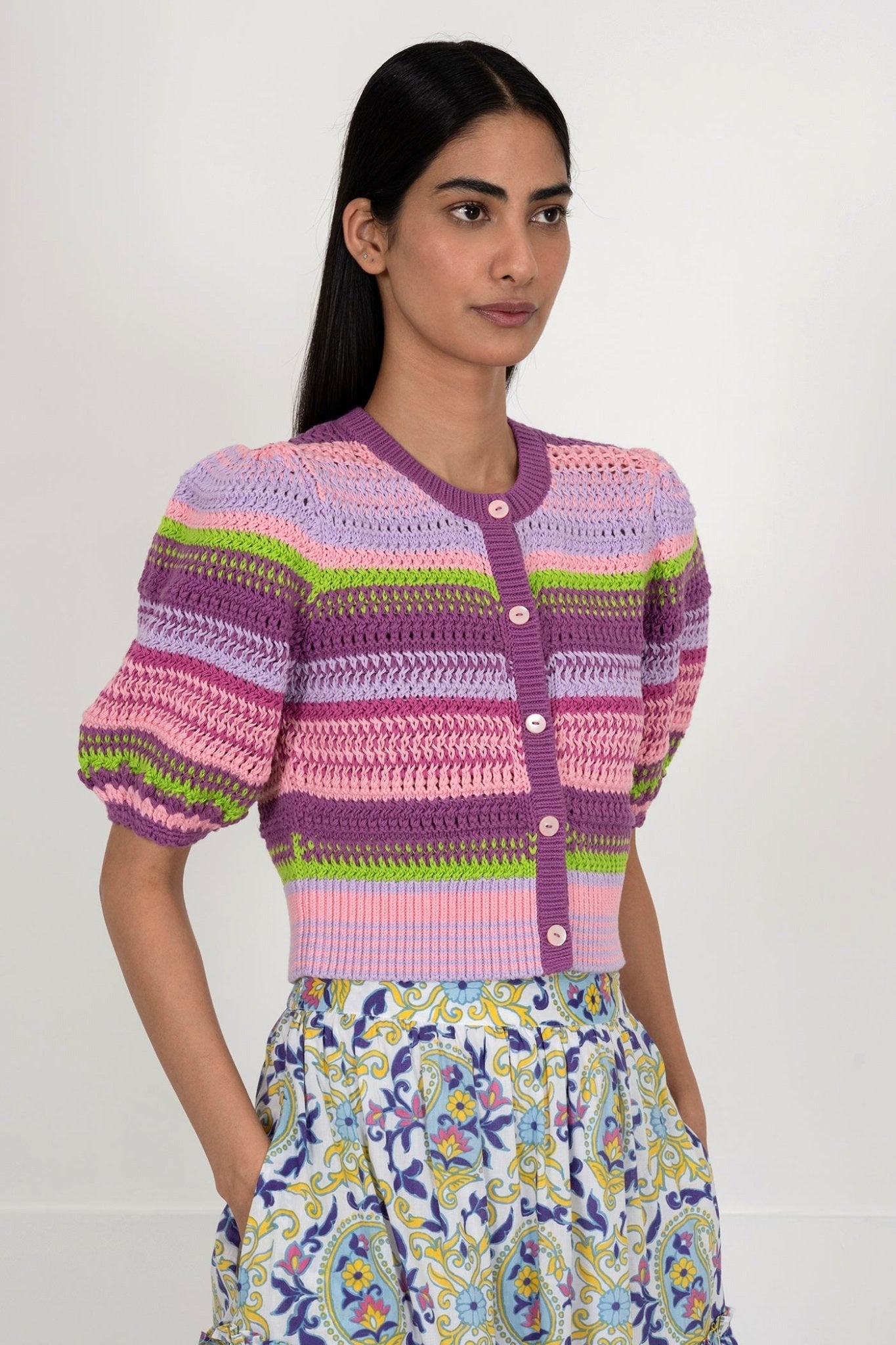 Side view of woman wearing the Celeste cardigan, a hand-crocheted piece in vibrant colors inspired by minerals. Perfect for layering over dresses or pairing with pants.