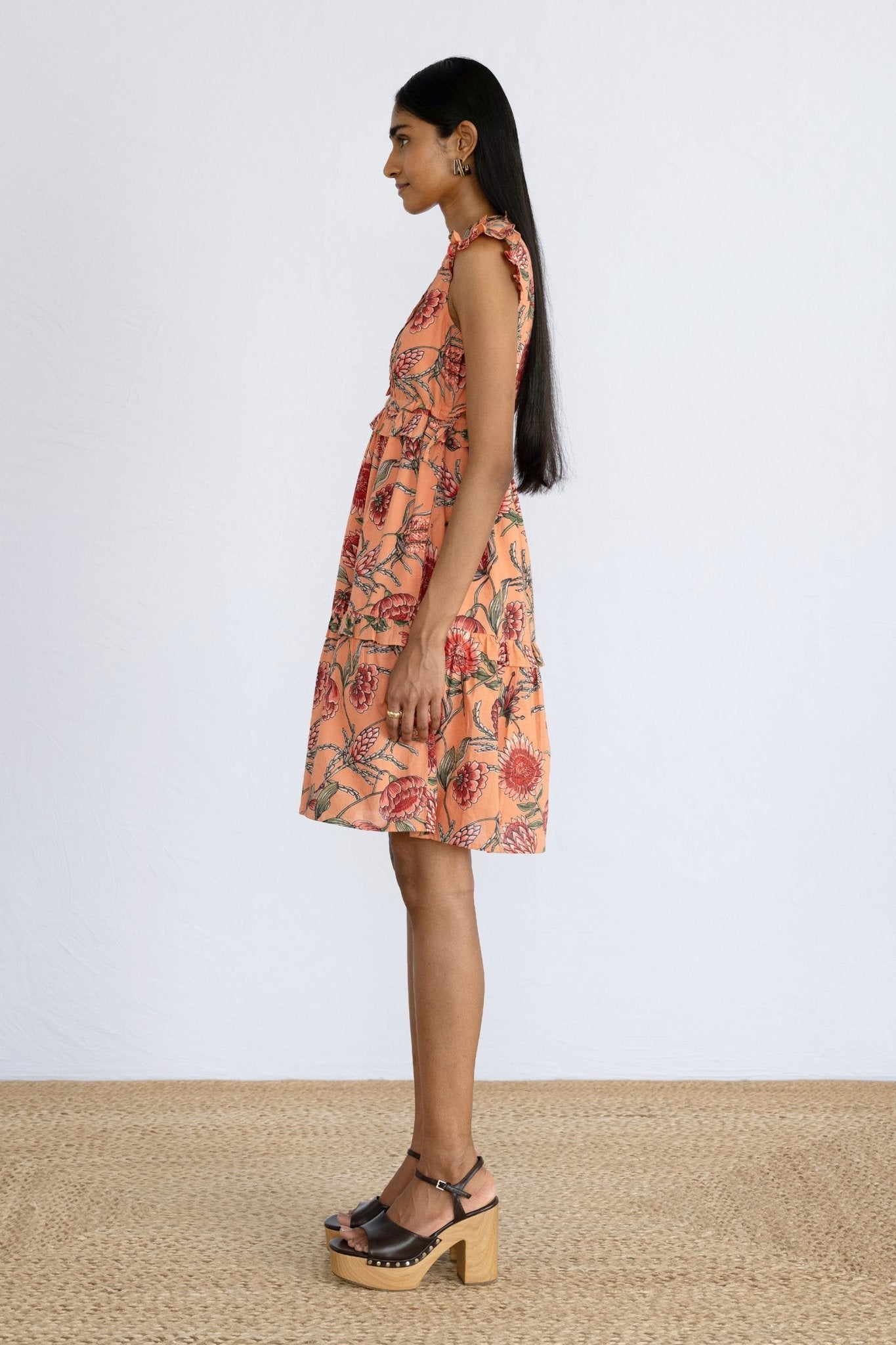 Side view of model standing, wearing a mini Chandra Dress in Protea Crabapple.