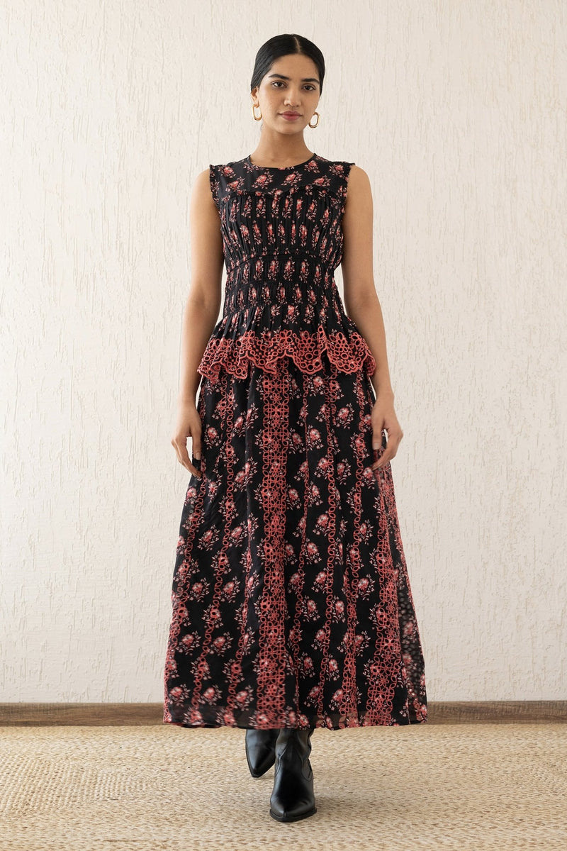 Front view of a woman wearing the Claudia midi dress sleeveless with a smocked sweetheart bodice, eyelet cutout details, and scalloped embroidery. It features the Butti Dusk print and has pockets.