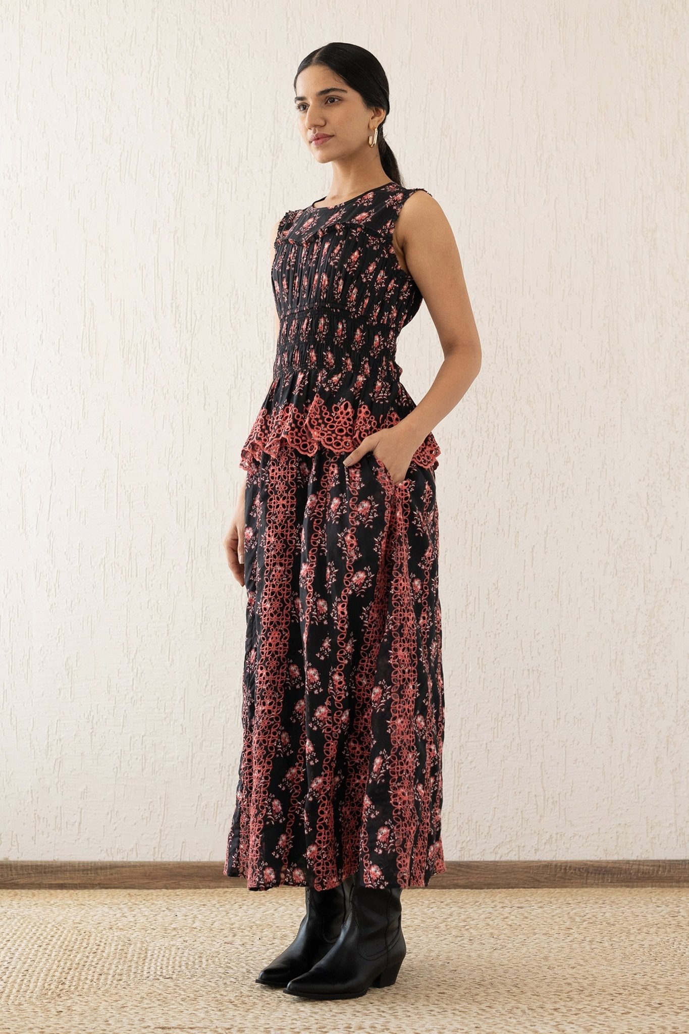 Side view of a woman wearing the Claudia midi dress sleeveless with a smocked sweetheart bodice, eyelet cutout details, and scalloped embroidery. It features the Butti Dusk print and has pockets.