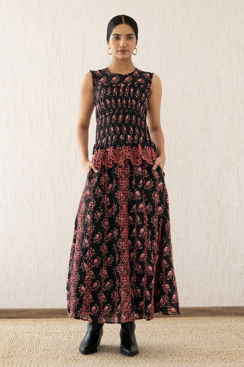 Front view of a woman wearing the Claudia midi dress sleeveless with a smocked sweetheart bodice, eyelet cutout details, and scalloped embroidery. It features the Butti Dusk print and has pockets.