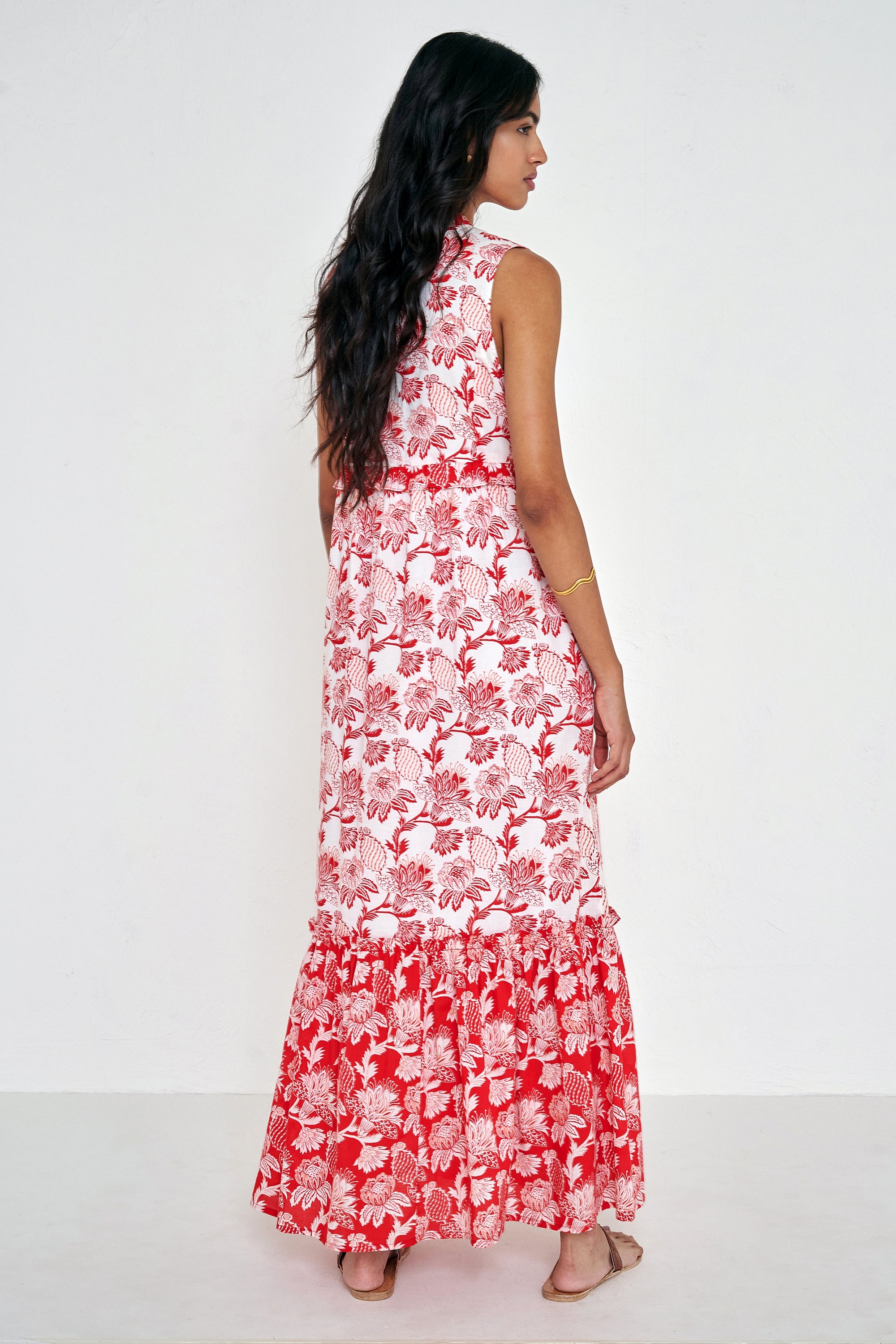 Back view of woman standing. She is  wearing the Constance dress in the Lizzie print, featuring an A-line silhouette, pleated neckline, soft frill details, and floral vine motifs inspired by Provence.