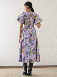 Back view of a woman wearing the Francesca dress in Vienna Waltz Lilac print, featuring a flattering V-neck, puffed sleeves, elastic under the bust, and side pockets.