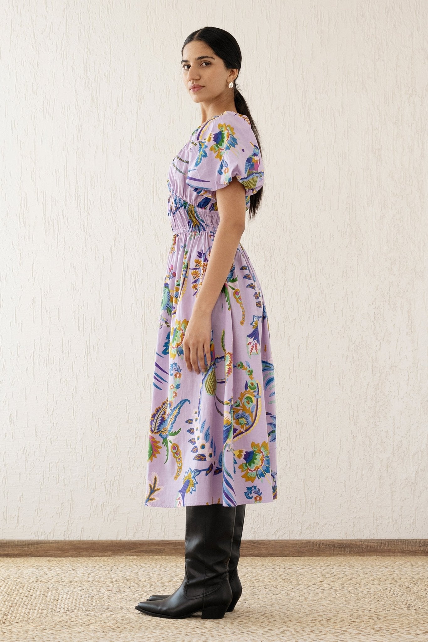 Side view of a woman wearing the Francesca dress in Vienna Waltz Lilac print, featuring a flattering V-neck, puffed sleeves, elastic under the bust, and side pockets.