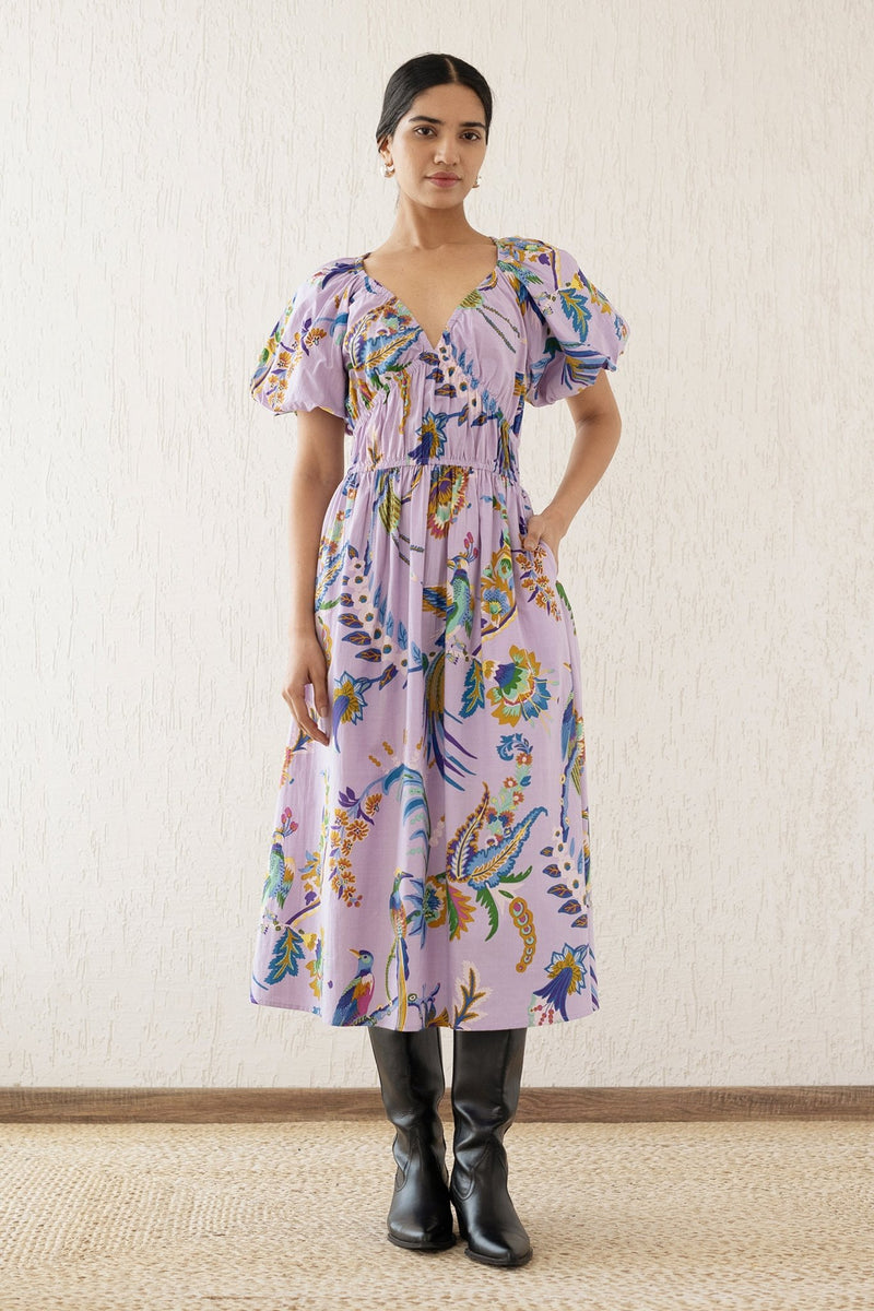 Front view of a woman wearing the Francesca dress in Vienna Waltz Lilac print, featuring a flattering V-neck, puffed sleeves, elastic under the bust, and side pockets.