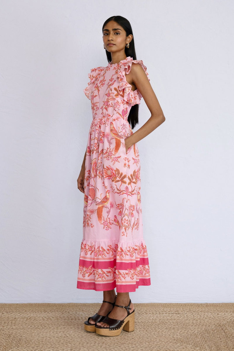 Side view of model standing wearing a full length Hannah Dress Botany Bay Pink Mist with a hand in pocket.