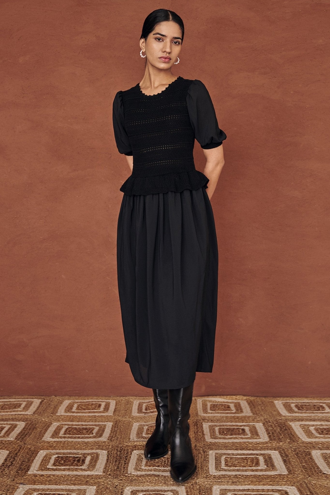 Front view of a woman wearing the Heather maxi dress in black, featuring hand-crocheted details, a woven viscose georgette skirt, and a soft peplum waist for a flattering silhouette.