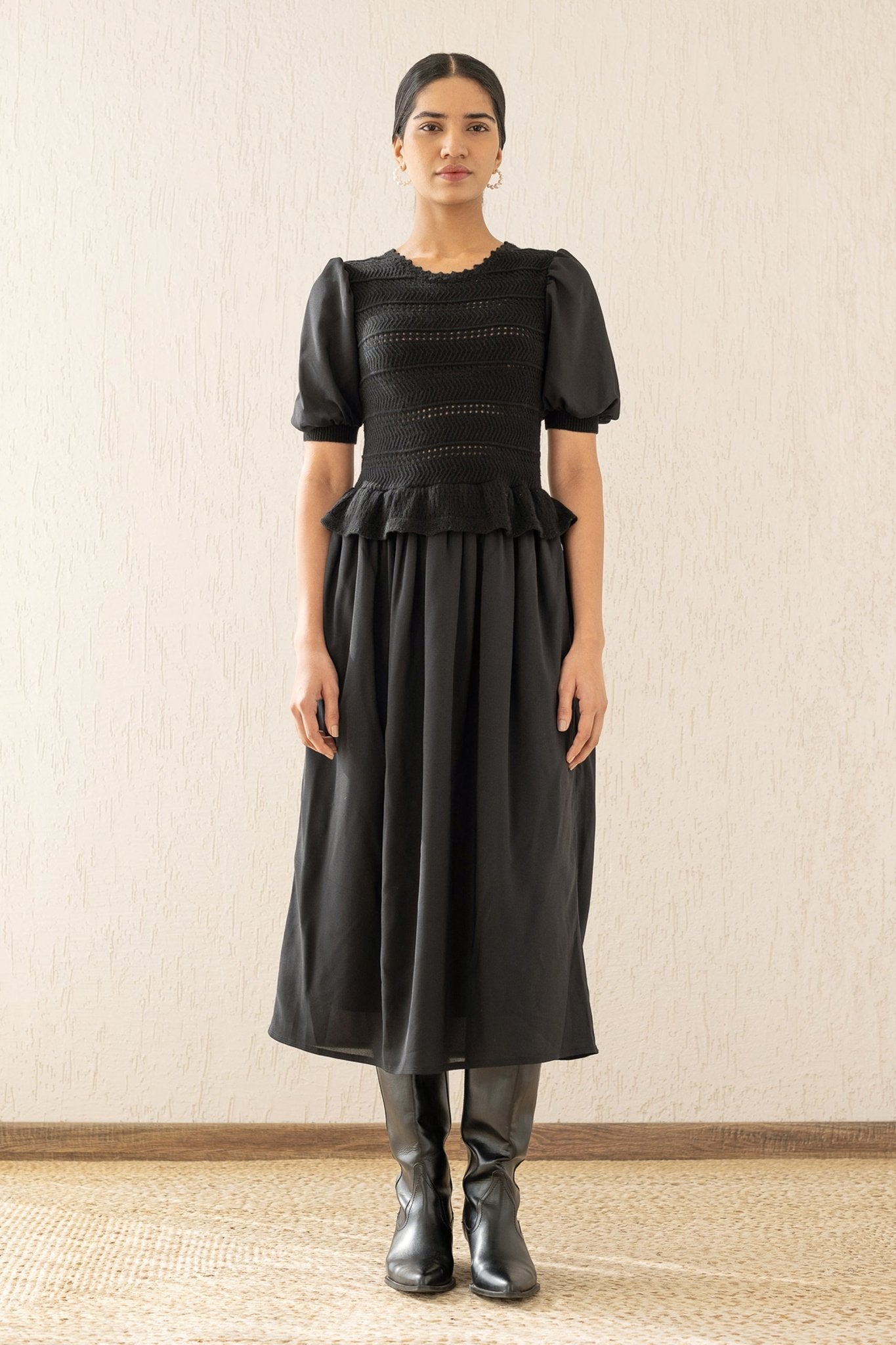 Front view of a woman wearing the Heather maxi dress in black, featuring hand-crocheted details, a woven viscose georgette skirt, and a soft peplum waist for a flattering silhouette.