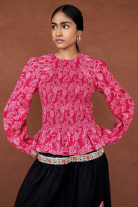 Front view close up of a woman wearing the Jaqueline top, featuring delicate smocking, slightly full sleeves, and a ruffled peplum waist in Tresse Winterberry floral print.