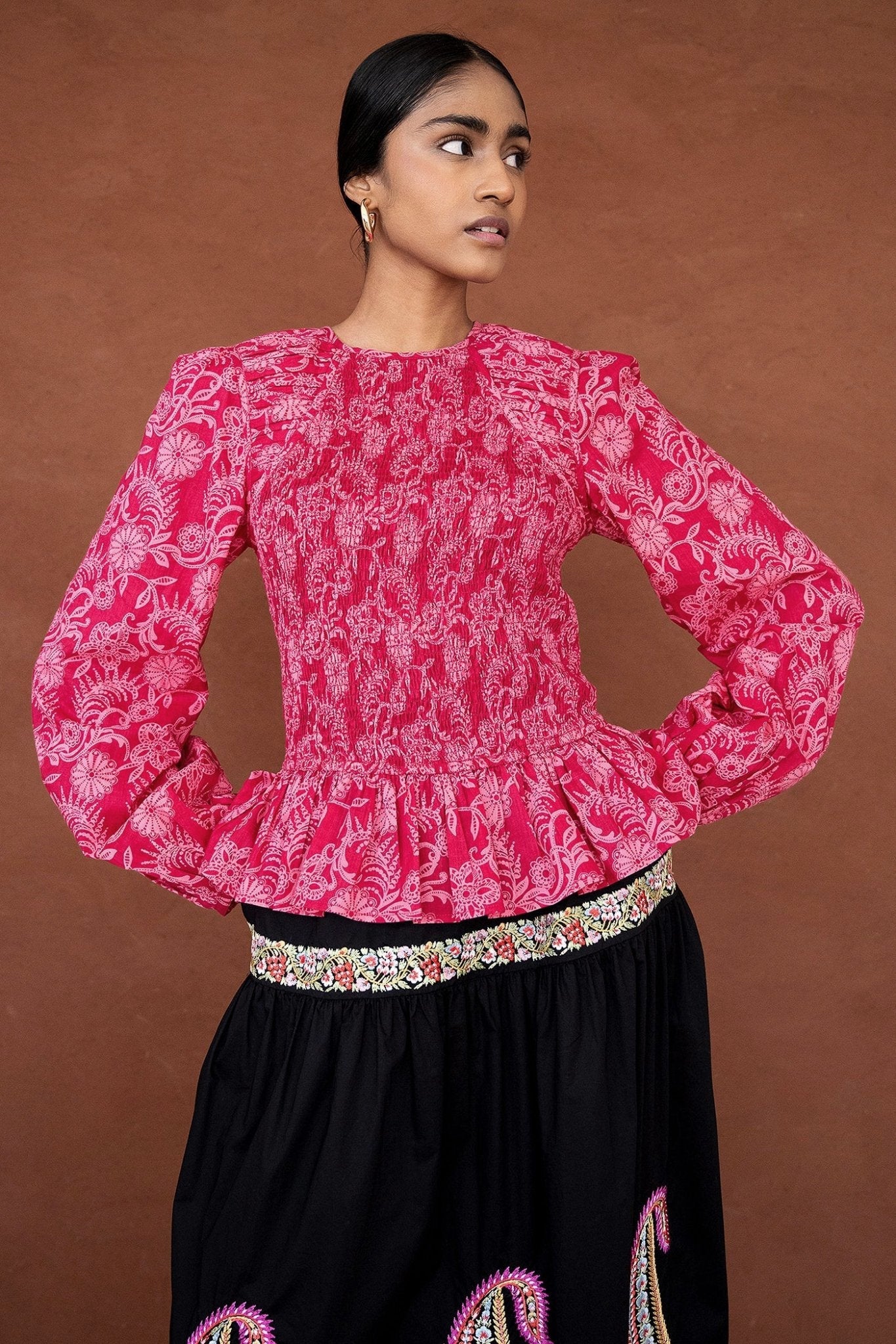 Front view close up of a woman wearing the Jaqueline top, featuring delicate smocking, slightly full sleeves, and a ruffled peplum waist in Tresse Winterberry floral print.