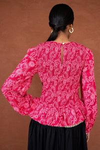 Back view close up of a woman wearing the Jaqueline top, featuring delicate smocking, slightly full sleeves, and a ruffled peplum waist in Tresse Winterberry floral print.