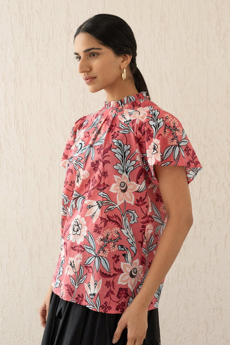 Close-up side view of a woman wearing the Joyful top with tucked raglan sleeves and a buttoned keyhole at the back, showcasing the bold Elisabetta Vine Rose print.