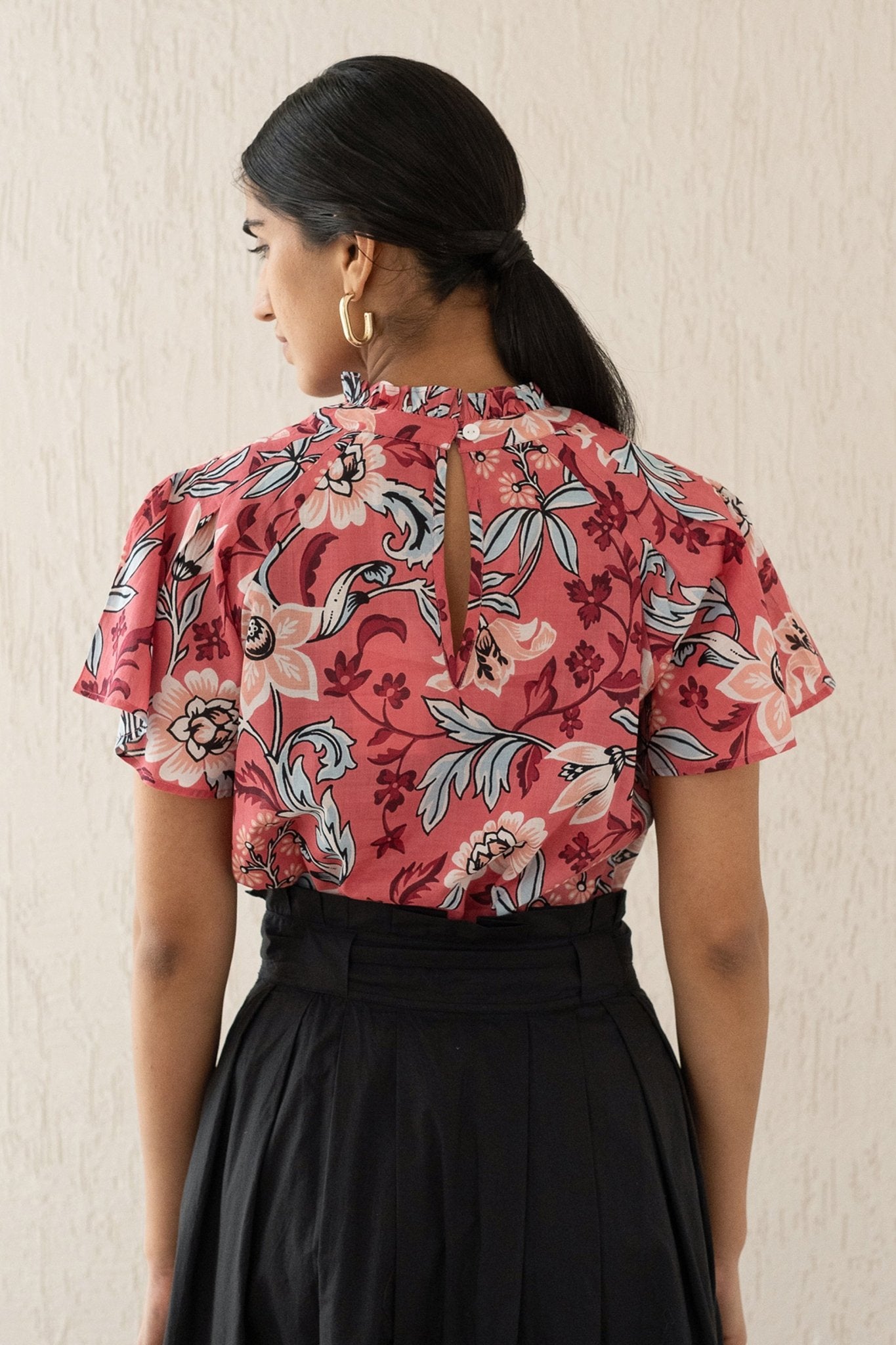 Close-up back view of a woman wearing the Joyful top with tucked raglan sleeves and a buttoned keyhole at the back, showcasing the bold Elisabetta Vine Rose print.