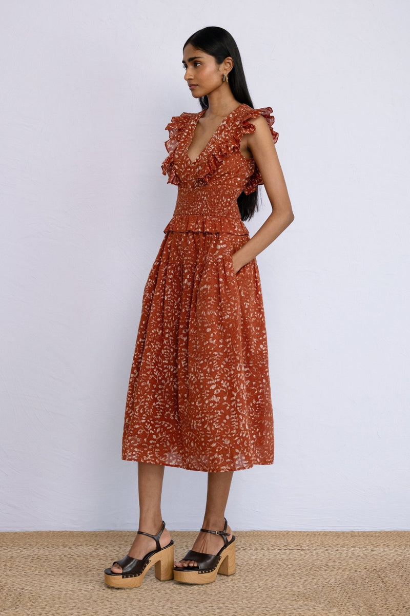 Side view of model wearing Keira Dress in block printed Bondi Batik print, Tobacco colour with hands in pocket.