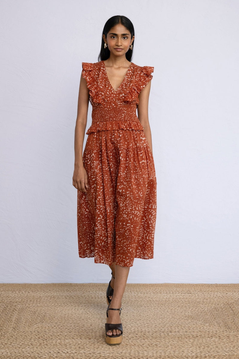 Front view of model stepping forward  wearing Keira Dress in block printed Bondi Batik print, Tobacco colour.