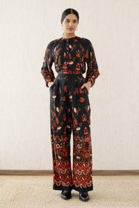 Front view of a woman wearing Killian Pant, a drapey trousers in Blumen Cedar print, featuring a fluid leg, front darts, and a drawstring waist with elastic for comfort.