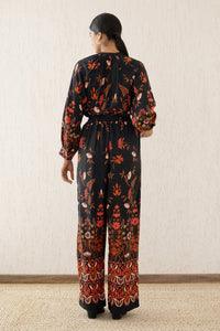 Back view of a woman wearing Killian Pant, a drapey trousers in Blumen Cedar print, featuring a fluid leg, front darts, and a drawstring waist with elastic for comfort.