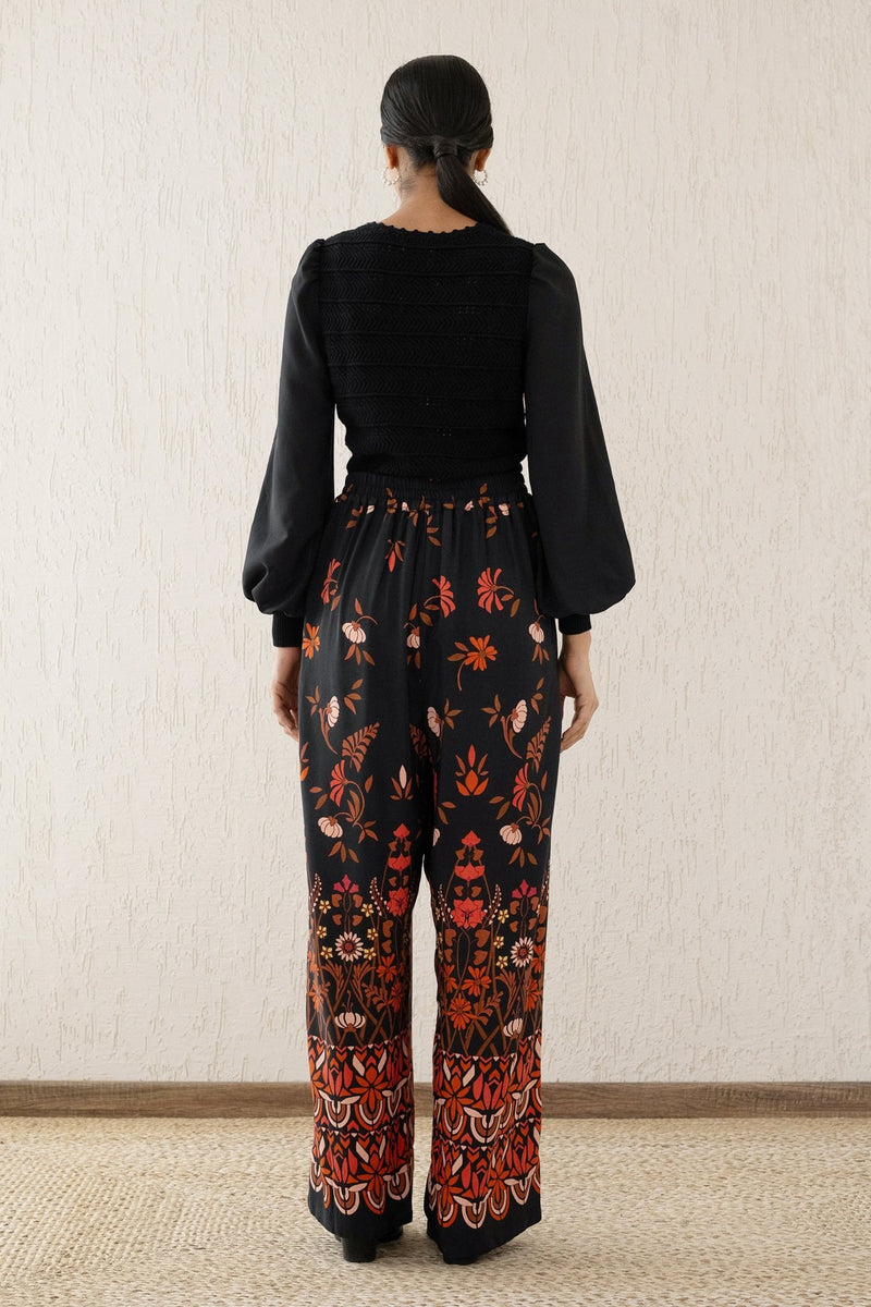 Back view of a woman wearing Killian Pant, a drapey trousers in Blumen Cedar print, featuring a fluid leg, front darts, and a drawstring waist with elastic for comfort.