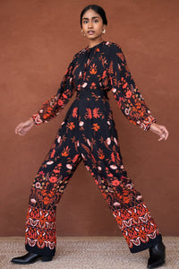 Side view of a woman wearing Killian Pant, a drapey trousers in Blumen Cedar print, featuring a fluid leg, front darts, and a drawstring waist with elastic for comfort.