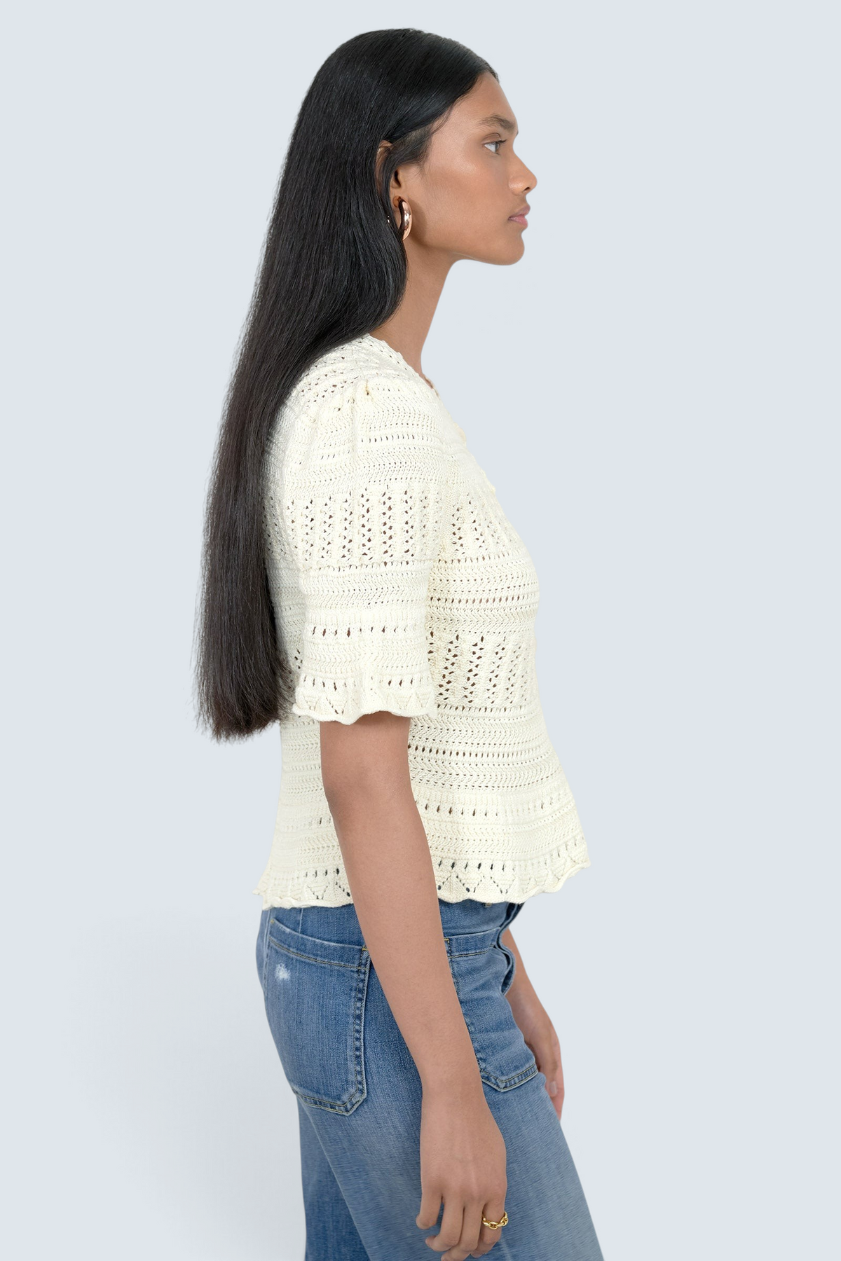 Model wearing a Banjanan ivory short sleeve cotton crochet cardigan with intricate trim detail, side profile view.