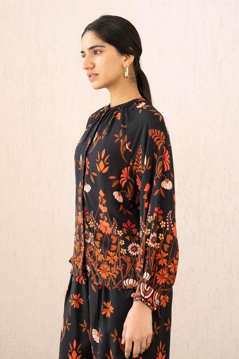 A close-up side view of a woman wearing the Leonie top in Blumen Cedar print, featuring soft gathers at the Mandarin collar and 3/4 raglan sleeves for a flattering drape.