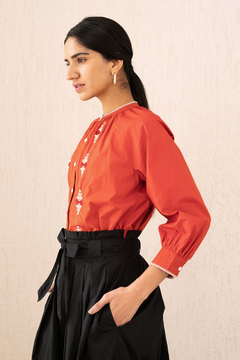 Close-up side view of a woman wearing the Leonie top sacher rooibos, featuring exquisite embroidery inspired by Austrian folk art, with soft gathers, a Mandarin collar, and 3/4 sleeves.