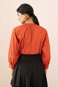 Close-up back view of a woman wearing the Leonie top sacher rooibos, featuring exquisite embroidery inspired by Austrian folk art, with soft gathers, a Mandarin collar, and 3/4 sleeves.