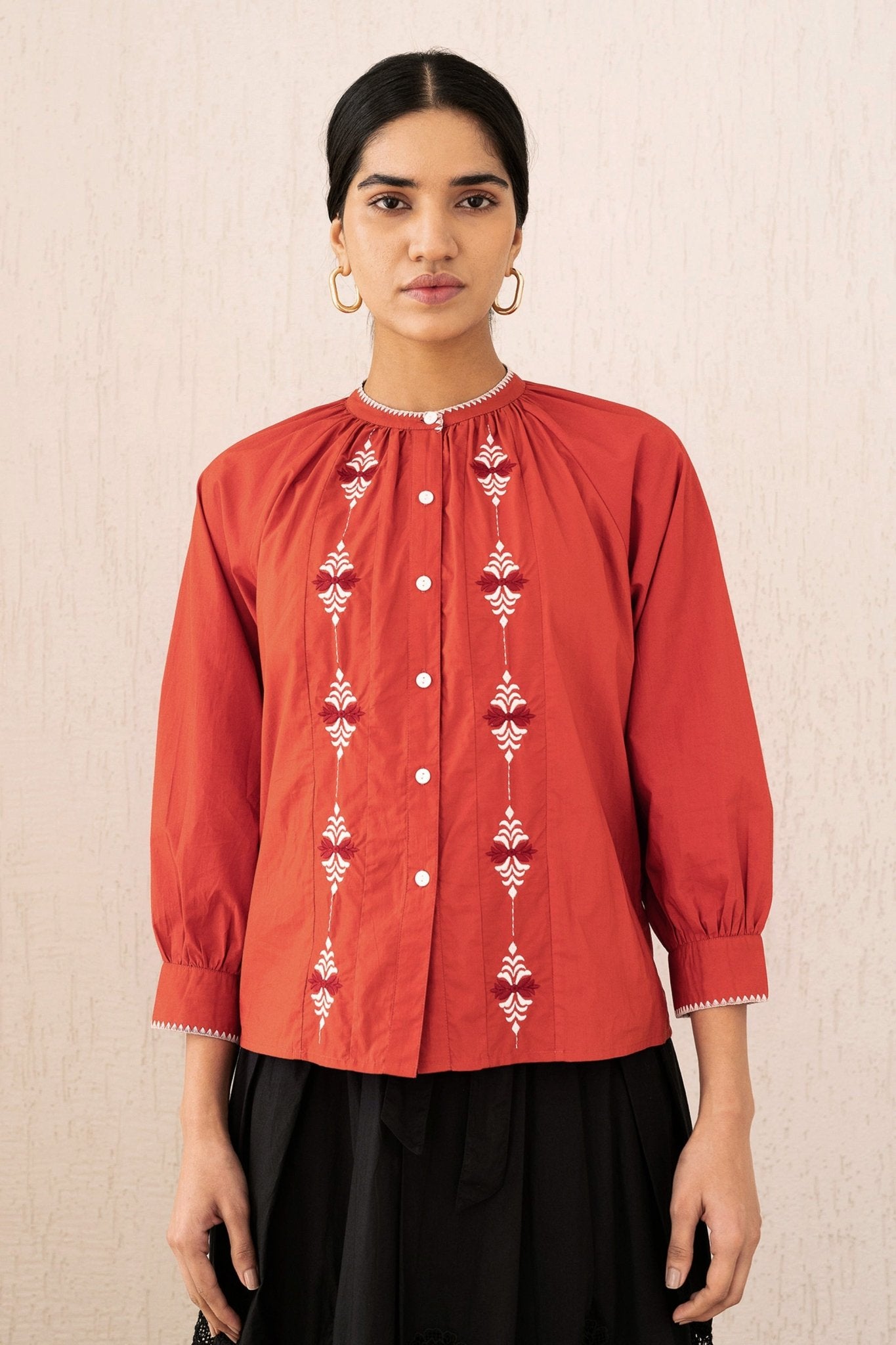 Close-up front view of a woman wearing the Leonie top sacher rooibos, featuring exquisite embroidery inspired by Austrian folk art, with soft gathers, a Mandarin collar, and 3/4 sleeves.