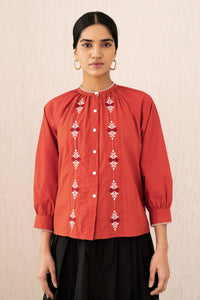 Close-up front view of a woman wearing the Leonie top sacher rooibos, featuring exquisite embroidery inspired by Austrian folk art, with soft gathers, a Mandarin collar, and 3/4 sleeves.