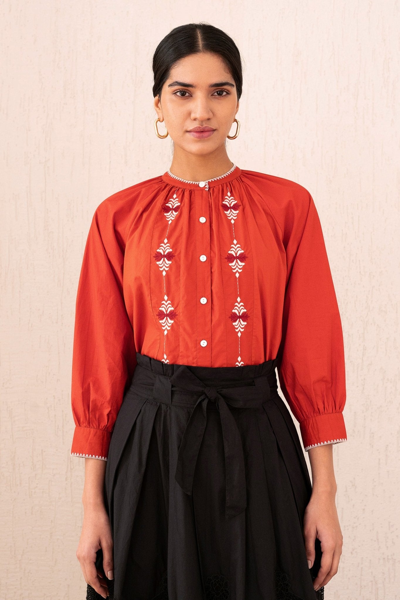 Close-up front view of a woman wearing the Leonie top sacher rooibos, featuring exquisite embroidery inspired by Austrian folk art, with soft gathers, a Mandarin collar, and 3/4 sleeves.