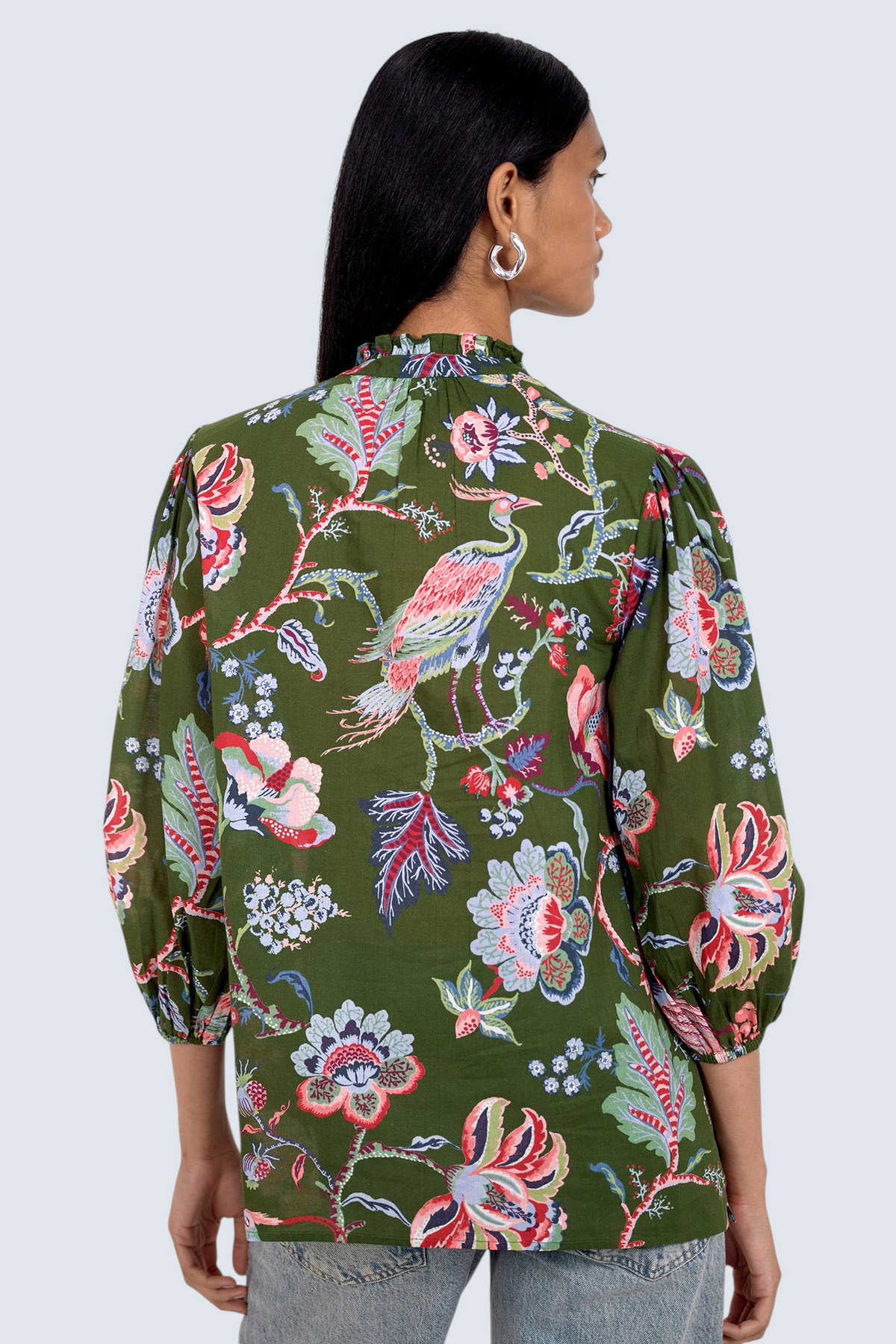 Back view of model standing. She is  wearing the Lorna top in Chintz print, featuring a V-neck with a soft ruffle and tie, a loose flowing body, and slightly voluminous sleeves, paired with jeans.