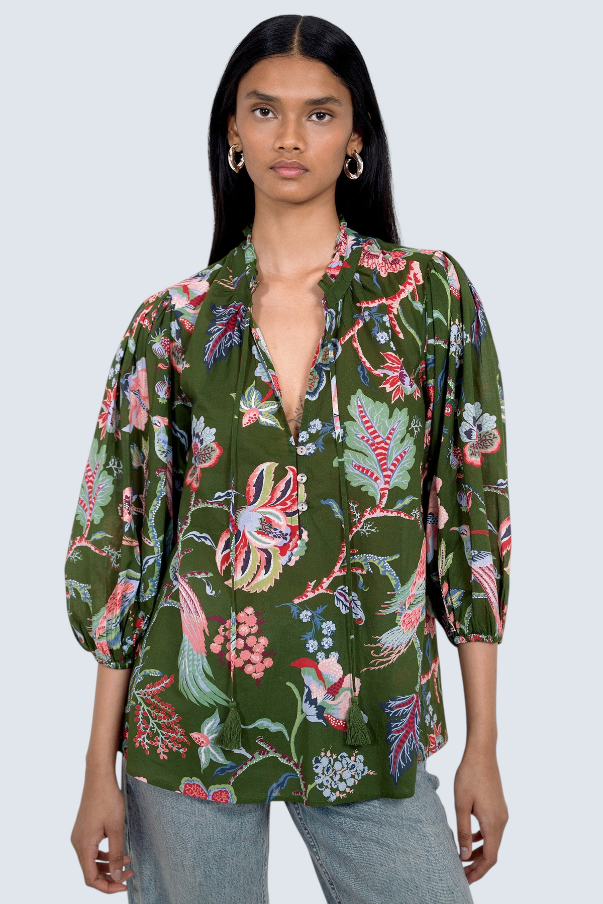 Front view of model standing. She is  wearing the Lorna top in Chintz print, featuring a V-neck with a soft ruffle and tie, a loose flowing body, and slightly voluminous sleeves, paired with jeans.