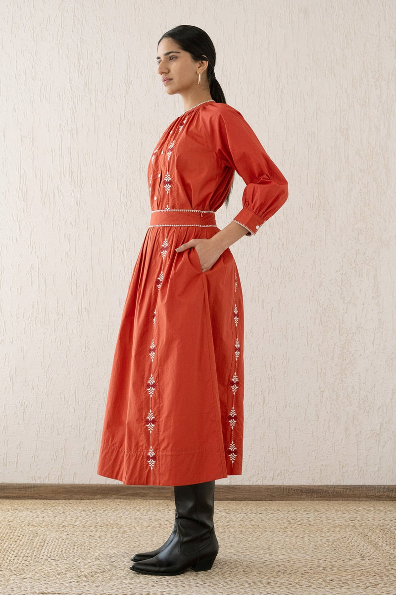 Side view of a woman wearing the Magdalena skirt Sacher Rooibos with a hand in pocket. It featuring exquisite embroidery inspired by Austrian folk art, side pockets, and a side zipper fastening.