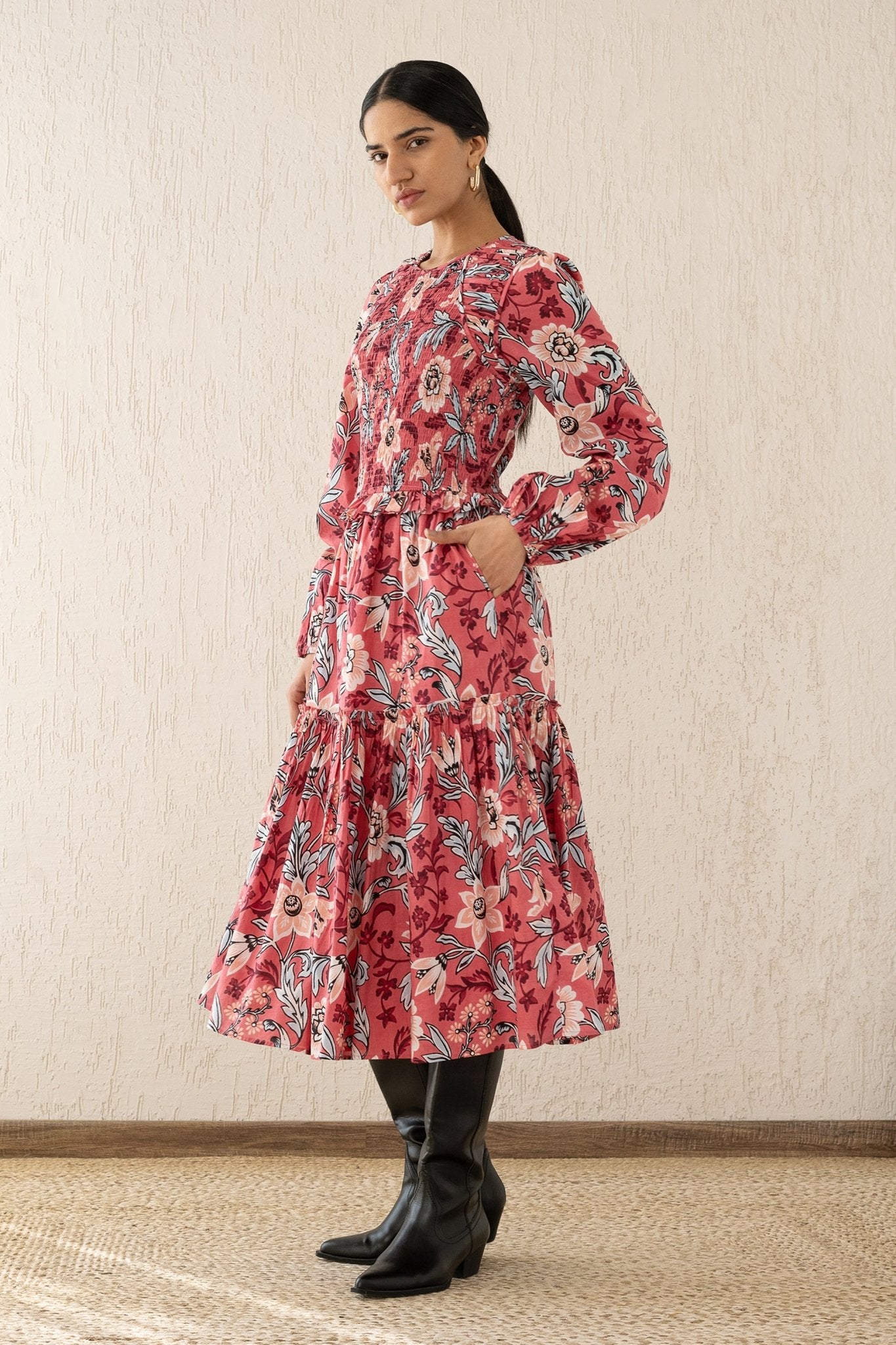 Side view of a woman wearing the Mortiz dress with smocked detailing, ruching at the shoulders, a tiered skirt, and frilled sleeves in Elisabetta Vine Rose print.