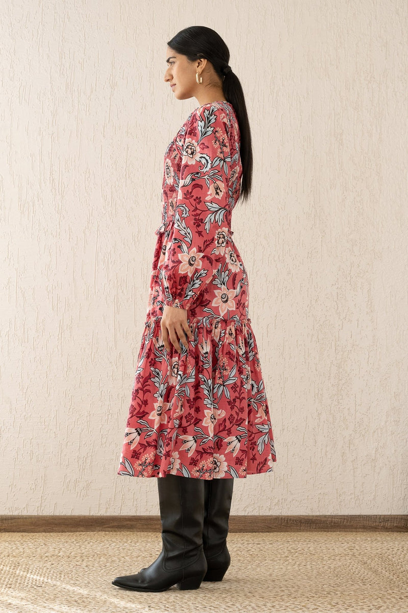 Side view of a woman wearing the Mortiz dress with smocked detailing, ruching at the shoulders, a tiered skirt, and frilled sleeves in Elisabetta Vine Rose print.