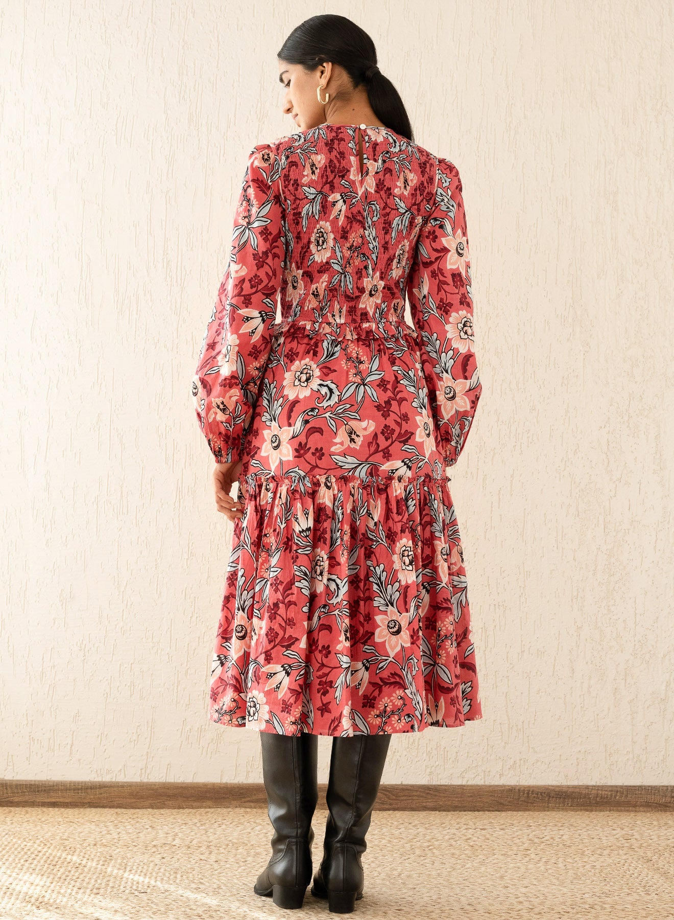 Back view of a woman wearing the Mortiz dress with smocked detailing, ruching at the shoulders, a tiered skirt, and frilled sleeves in Elisabetta Vine Rose print.