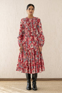 Front view of a woman wearing the Mortiz dress with smocked detailing, ruching at the shoulders, a tiered skirt, and frilled sleeves in Elisabetta Vine Rose print.