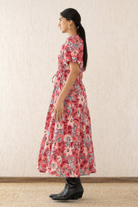 Side view of a woman wearing the Poppy dress, featuring raglan blouson sleeves, a button placket, a flowing skirt, and a drawstring waist in Elisabetta Vine Rose floral print.