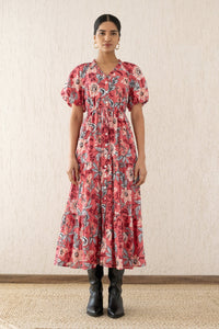 Woman standing straight wearing the Poppy dress, featuring raglan blouson sleeves, a button placket, a flowing skirt, and a drawstring waist in Elisabetta Vine Rose floral print.