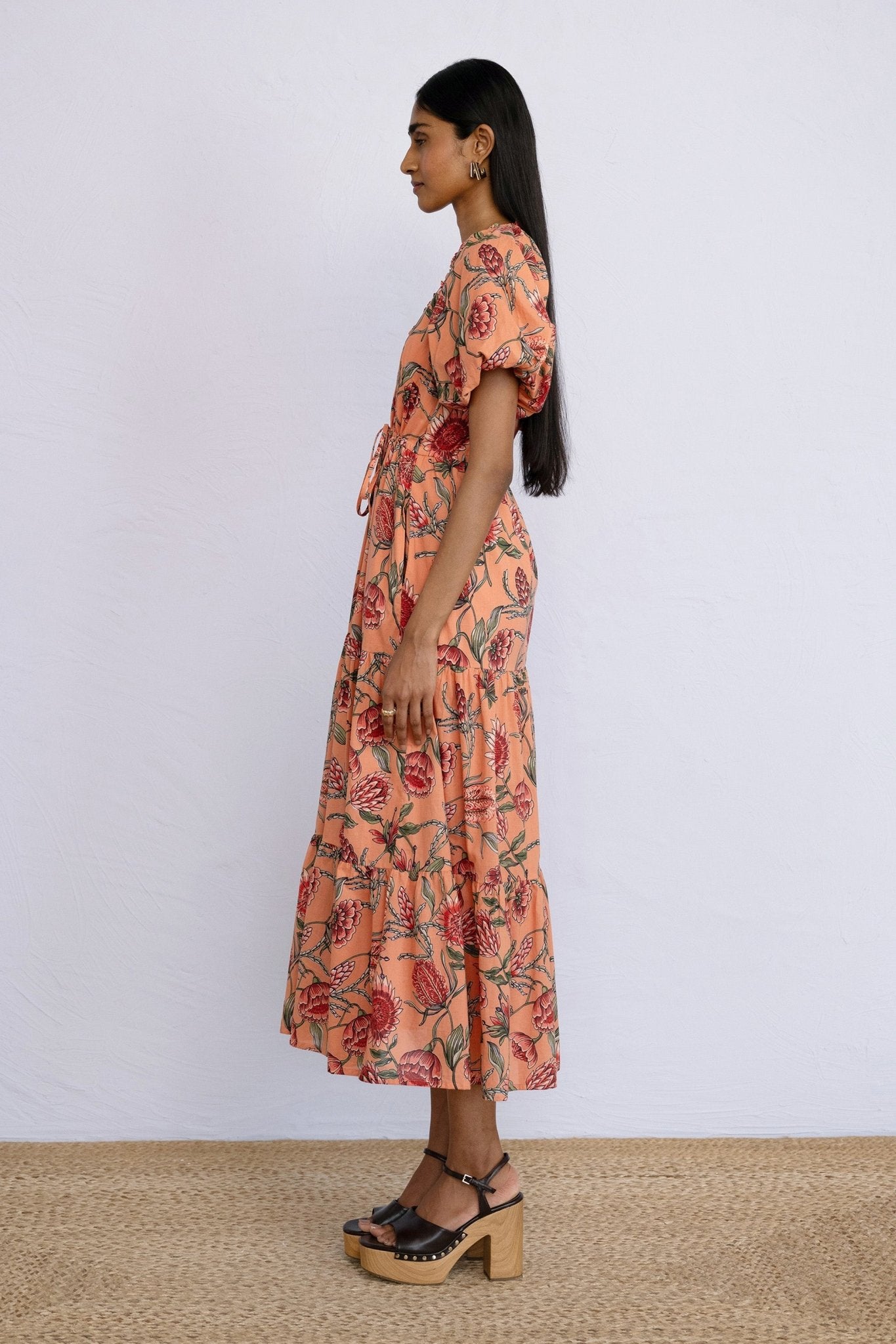 Side view of model wearing a calf length Poppy Dress in Protea Crabapple print.