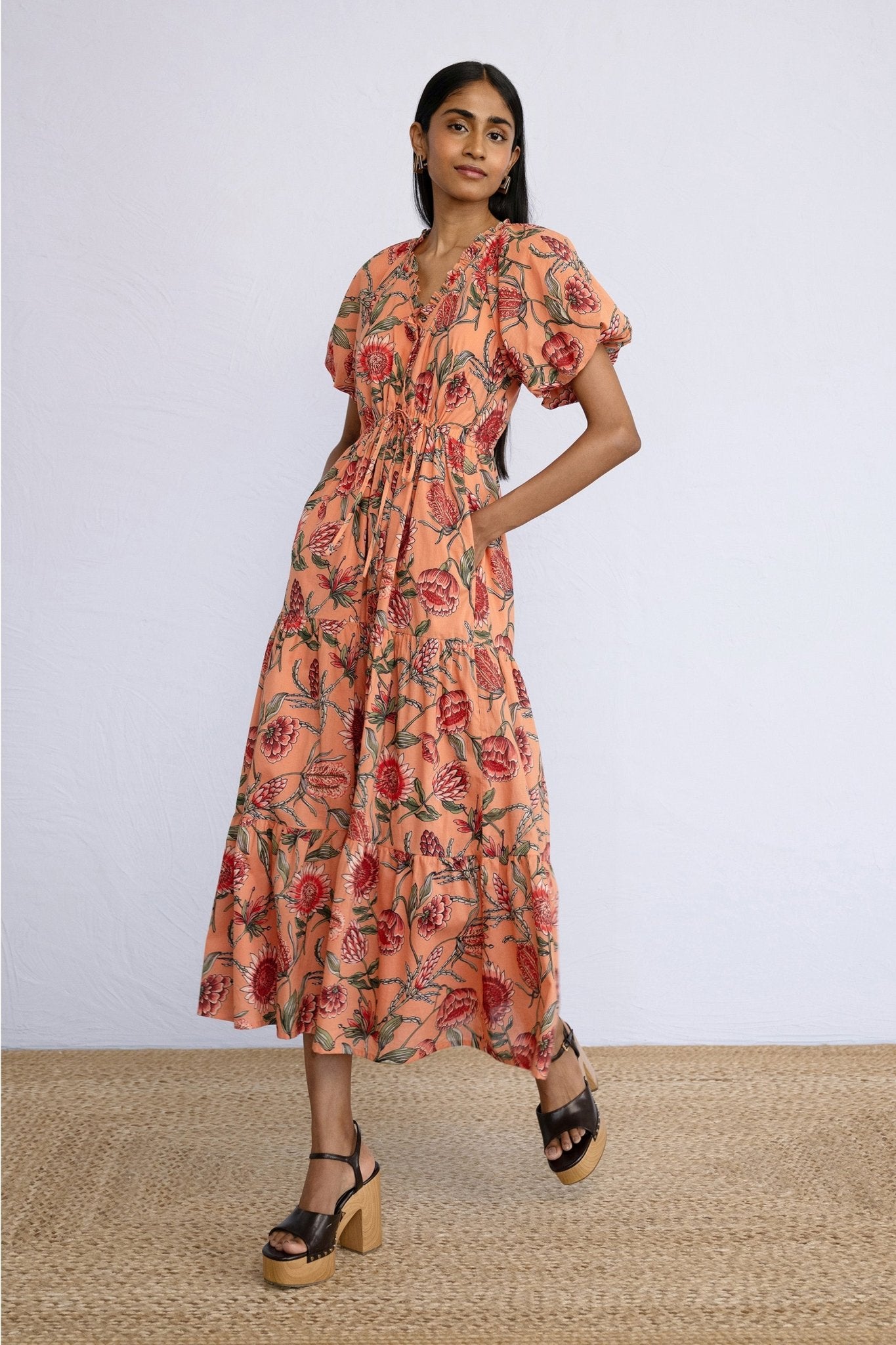 Side view of model wearing a calf length Poppy Dress in Protea Crabapple print.