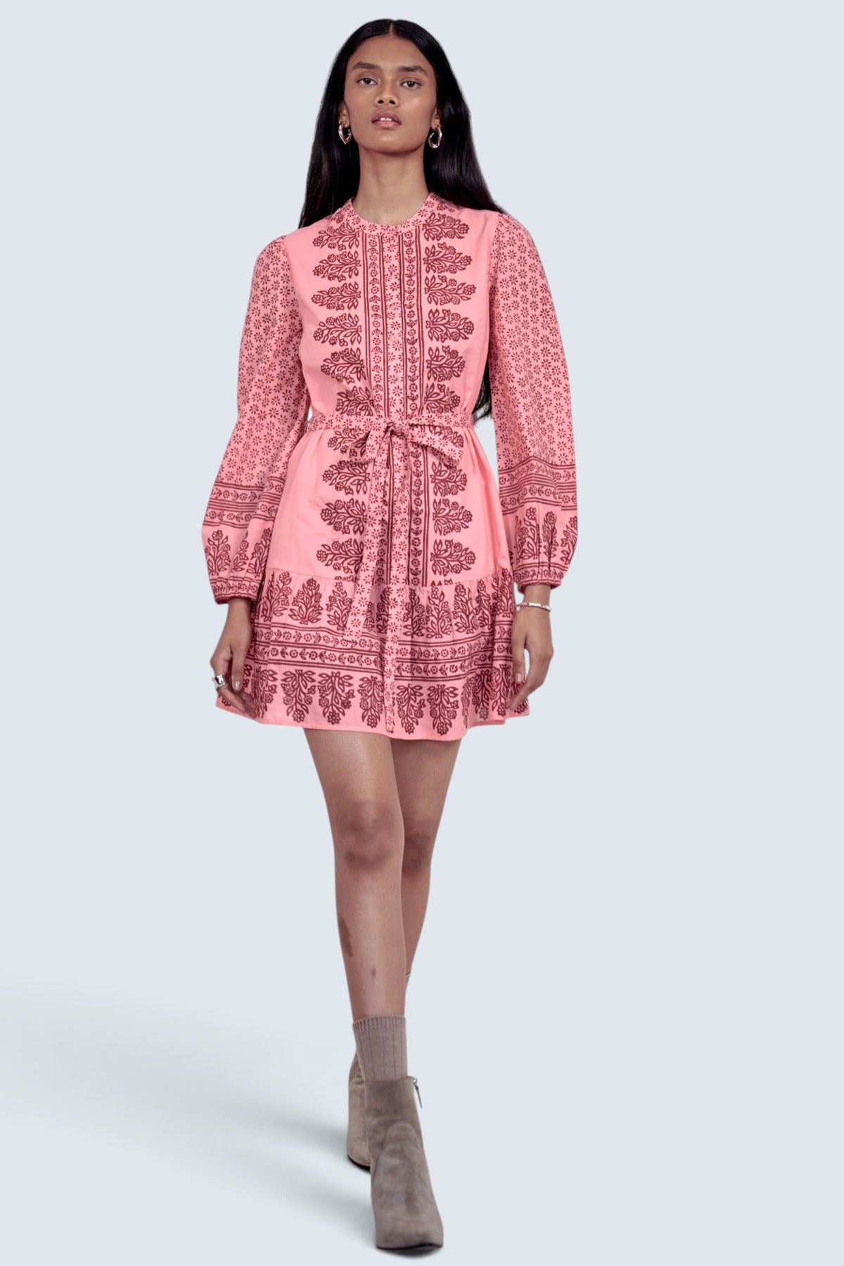 Front view of model walking forward. She is wearing the Roma dress in Eugenie print, featuring a mini length, wrist-length sleeves, a detachable belt, and side-seam pockets.