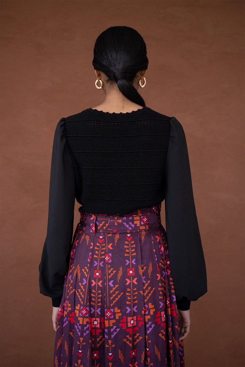 Back view of woman wearing the Rosie knit, featuring hand-crocheted details and viscose georgette sleeves, blending structure with textural complexity.